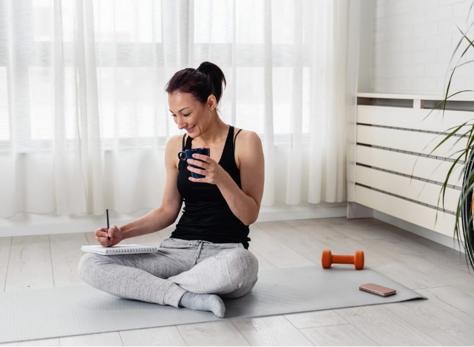 Young woman writing in her notebook her fitness goals