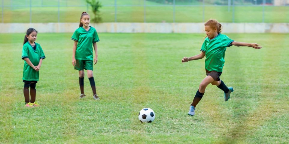 Girl kicks soccer ball during game