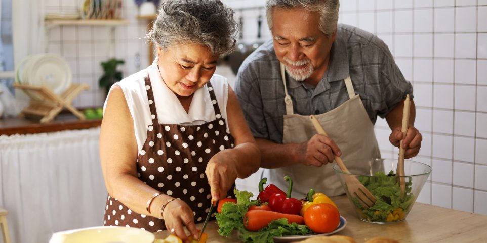 Happiness senior elderly couple having fun in kitchen with healthy food for working from home.