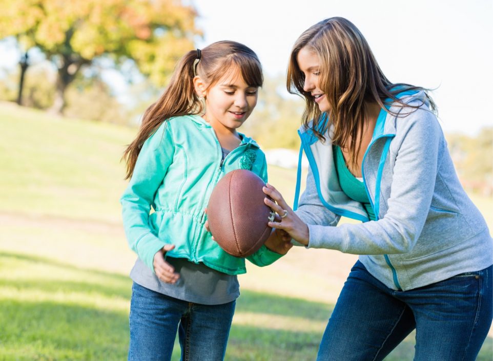 One of the football moms playing football with her young daughter.